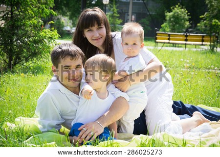 Happy beautiful young family dad mom and sons lie on the grass in the summer to enjoy nature outdoors