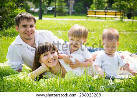 happy young family dad mom and sons lie on the grass in the summer to enjoy nature outdoors