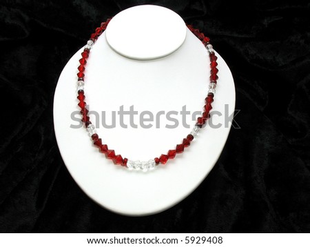 This is a glass bead necklace on a white display stand with a black velvet background.