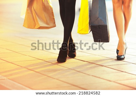 Legs of two glamorous girlfriends with paperbags. Big Sale Shopping
