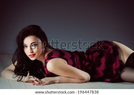 Pin up girl lying on the wooden floor in dress and stockings