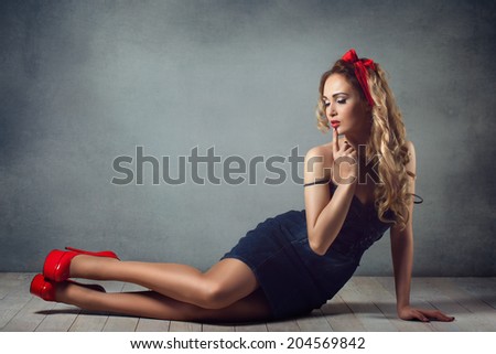 sexy blonde woman in jeans sundress and red shoes pin up girl retro woman sexy legs and a red capitium on his head crawling on the floor  sitting on the floor and straightens hair