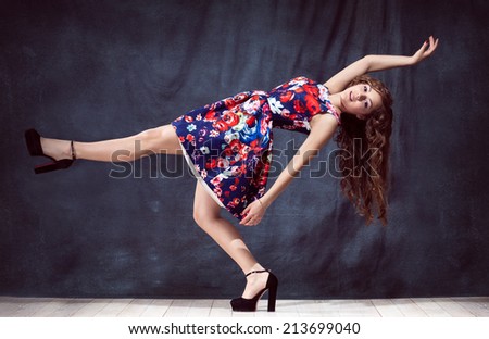 young beautiful girl falls in colored dress with makeup and long hair in natural black shoes in the studio