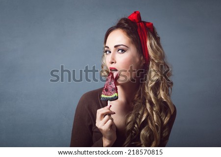 Portrait of beautiful young sexy blonde with a red armband with red lips with lollipop  form watermelon lollipop licking tongue sensual temptation to make up pin up