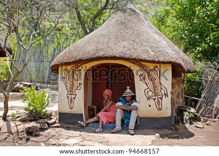 CULTURAL VILLAGE LESEDI,SOUTH AFRICA-JANUARY 1: An unidentified African sotho couple in handmade dress sitting near native tribal house on January 1,2008. Sotho are distinguished by colorful blankets and conical hats.