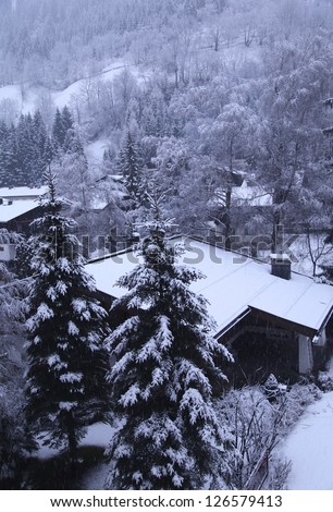 Snow Covered huts and trees in Alps Mountain, gray winter day (Austria). Snowing