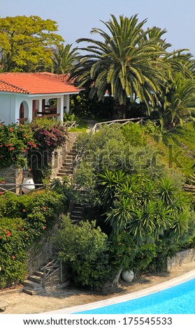 Beautiful white house with red tile roof, steps and swimming pool in the mediterranean garden(Greece).