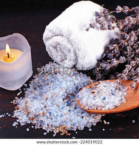 spa composition with natural lavender bath salt, candle and dry lavender on dark wood background