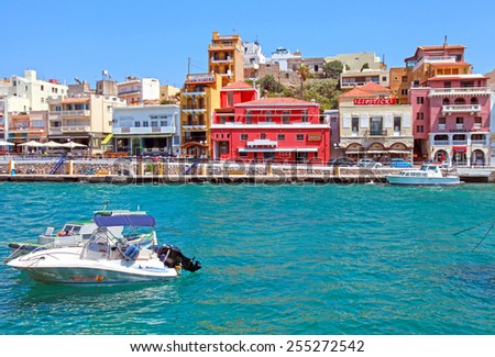 AGIOS NIKOLAOS, GREECE - JULY 18, 2012: Waterfront with outdoor greek tavern, small shops and boats in harbor of Agios Nikolaos, Crete, Greece.