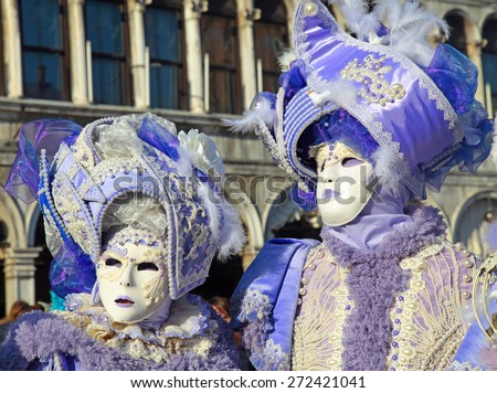 VENICE, ITALY - FEBRUARY 8, 2015: Two unidentified masked persons in ornate lilac medieval costume on San Marco Square during the Carnival in Venice, Italy.