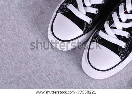 A pair of black canvas sneakers on grey textile background with copyspace