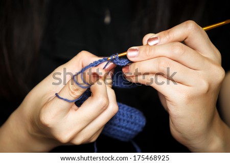 A women is knitting a blue crochet.