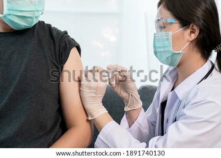 Asian professional doctor injecting a Coronavirus 2019-nCoV or COVID-19 vaccine at male patient arm close up, COVID19 vaccinating about protecting and build antibody - immunity against Coronavirus.