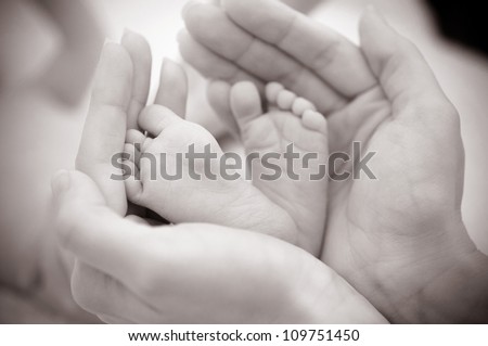 Baby feet cupped into mothers hands.