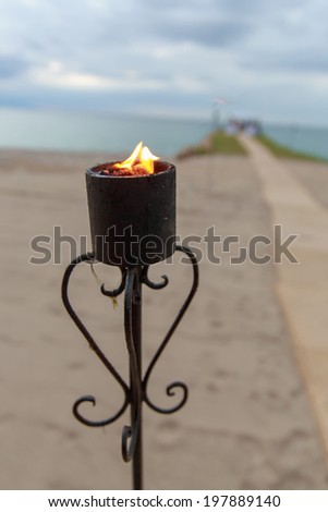 oceanfront wedding at sunset with lit torches. Focus is on torch.