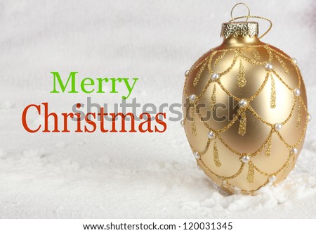 Merry Christmas and a bulb in gold. Snow in the background