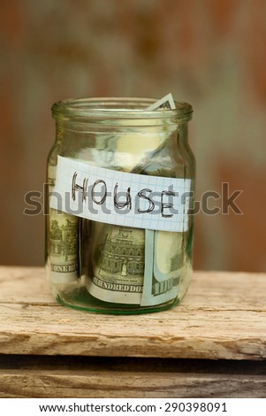 Dollar in glass jar with house label, financial concept.