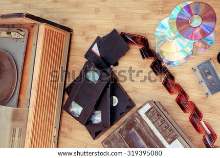 Old subjects of 80-90 years: a record player, video of the cartridge, disks, the cartridge and a film on a wooden background