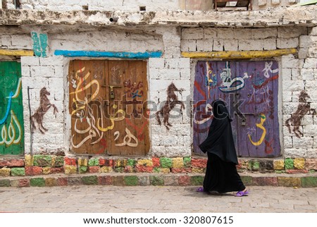 IBB, YEMEN - MAY 10, 2007: An unidentified woman walks in a street with graffiti. Modern day women of Yemen do not hold many economic, social or cultural rights.