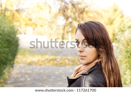 Head and shoulders portrait of a beautiful trendy woman standing outdoors looking back at the camera over her shoulder with copyspace
