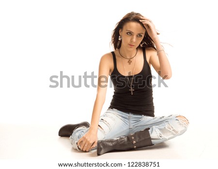 Beautiful casual young woman or student with a shapely slender body sitting on the floor with her hand to her forehead looking off into the distance on a white studio background