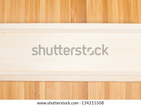 Natural light wood banner formed from the partial view of a wooden kitchen utensil place horizantally over darker wood with a definite woodgrain pattern