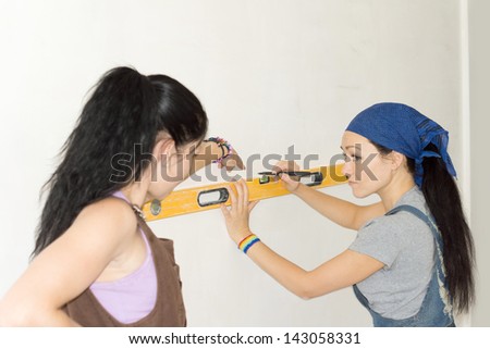 Portrait of woman explaining how to use spirit level to female carpenter
