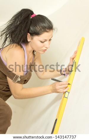 DIY young attractive woman using spirit level to work out measurements.
