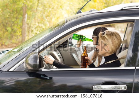 Two women driving a car on a rural road while drinking alcohol from the bottle in a case of dangerous driving