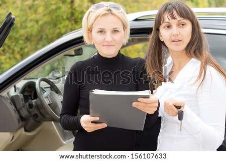 Two women checking a contract or paperwork before finalising the deal on the purchase of a new car