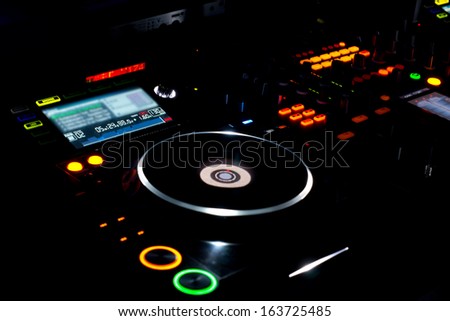 Colourful turntable and LP vinyl record on a DJ music deck at a disco, concert or party for mixing music and recorded soundtracks