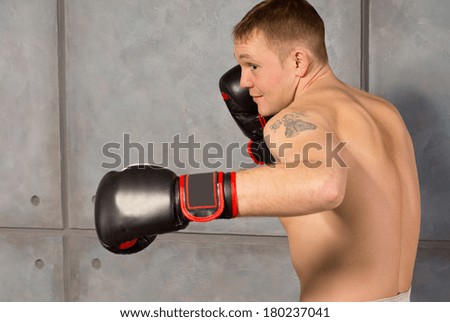 Muscular young boxer facing off with his fist raised to protect his head as he seeks on opening for a punch, close up side view