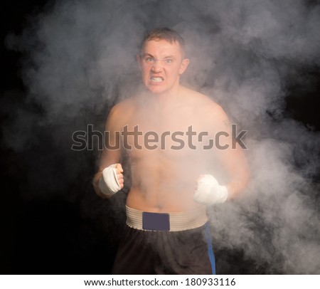 Ferocious determined boxer snarling and gritting his teeth as he fights in a smoke filled dark environment