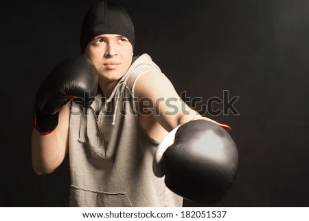 Young boxer working out in a training session frowning as he does not quite manage to pull off the punch correctly on a dark background