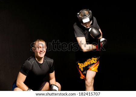 Young boxer ducking under his opponents punch with a smile of glee as the man is pulled off balance by the power of his own punch