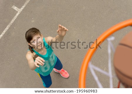 Athletic young girl scoring a goal in basketball as the ball enters the net, view from on top of the net as the ball passes through looking down on the girl