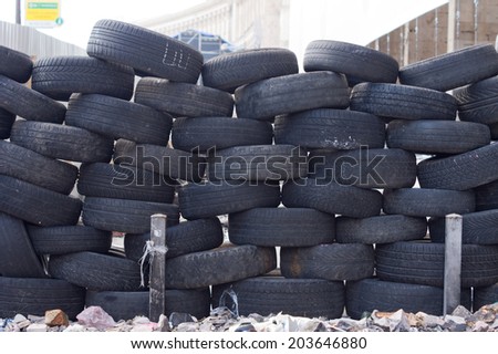 Old tires stacked to form a barricade or wall at a fairground to provide a safety feature for participants on rides and amusements