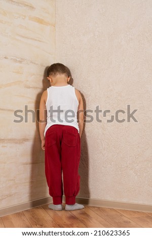 White Little Boy Facing Wooden Walls. Very Shy Looking at Camera