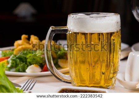 Mug of refreshing cold beer with a good frothy head served at table with a formal meal