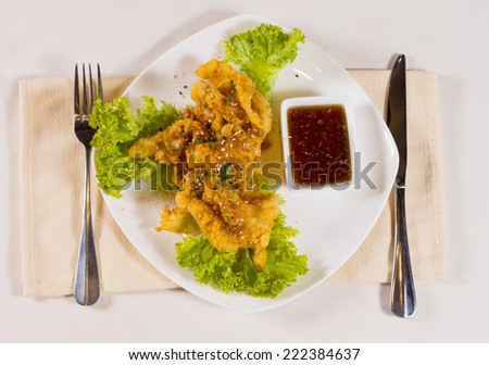 Close up Tasty Crispy Fried Chicken Meat above Fresh Lettuce Recipe with Hot Dip Sauce. Served on the Table with Utensils on Sides.