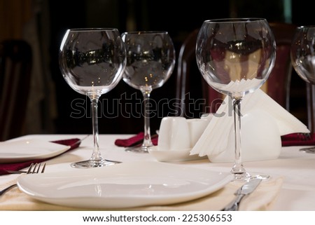 Empty plate and wineglasses on a formal dinner table in a restaurant, low angle view