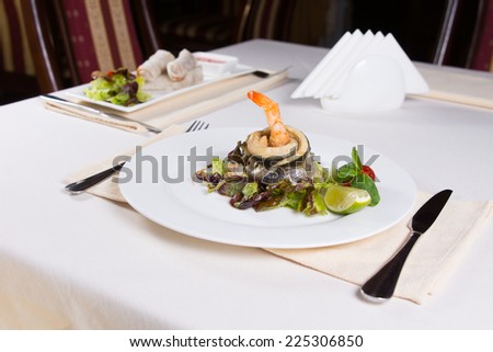 Gourmet Seafood Dish with Fish Meat and Shrimp on Vegetables with Lemon. Prepared on White Round Plate. Served on the Table at the Restaurant.