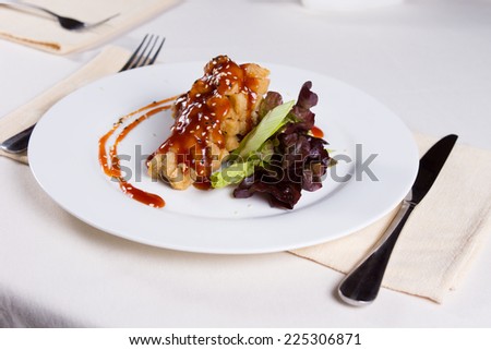 Crispy Fried Chicken Main Dish with Sauce on Vegetables. Prepared on White Round Plate at the Table.