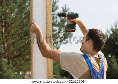 Close up Male Construction Worker Drilling on Wooden Plank During Building a House.