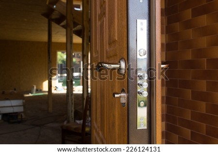 Safety lock on a new wooden front door showing the three security cylinders required by insurance companies for best premium quotations