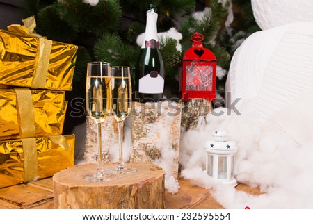 Christmas celebration with champagne in stylish glass flutes with luxury gold gifts, a festive lantern and a snowman