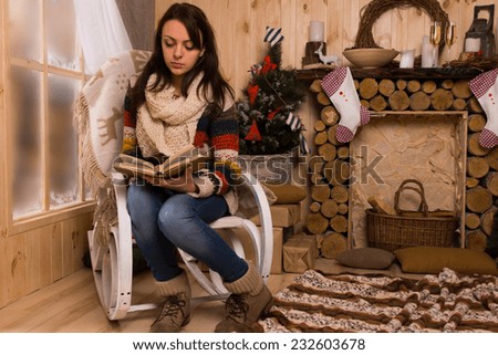 Woman Reading Book in Chair next to Mantle in Rustic Cabin at Christmas Time
