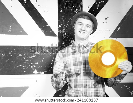 Close up Smiling Man in Monochrome Style Holding Golden Vinyl Record Plate in Front UK Flag Print.