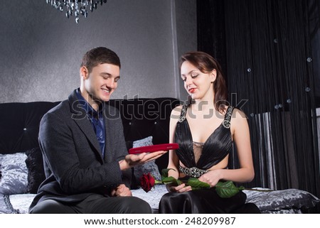 Close up Happy Young Man Offering Jewelry in Red Box to Pretty Woman at the Bedroom.