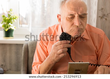 Close up Old Man Shaving Beard with Electric Razor Seriously in Front Small Mirror